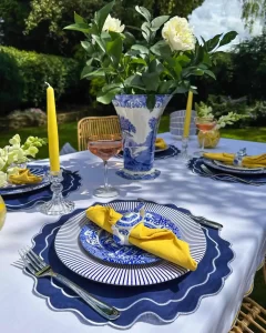 تصویری از یک میز ناهارخوری شیک در فضای باز که یک فضای دوستانه را تداعی میکند و رنگ های زرد و سورمه ای و طبیعت سرسبز